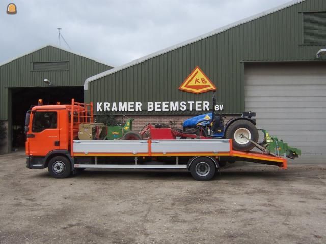 Oprijwagen vervoert landbouwmachine op laadplatform bij agrarisch bedrijf