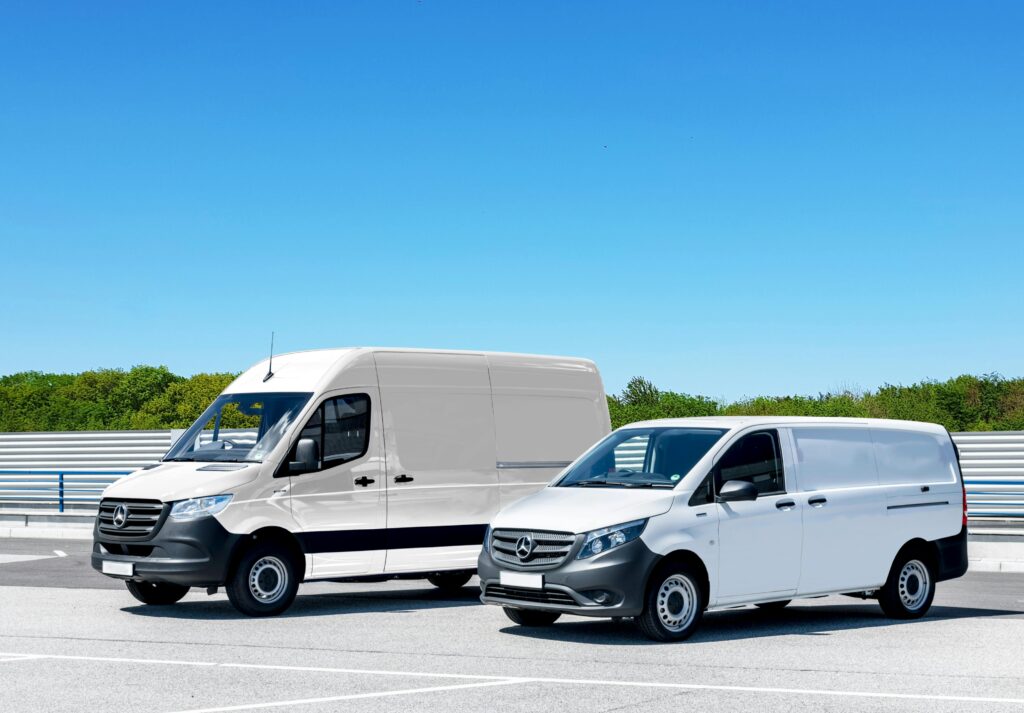Twee witte bestelwagens geparkeerd op open terrein voor zakelijk transport en logistiek gebruik