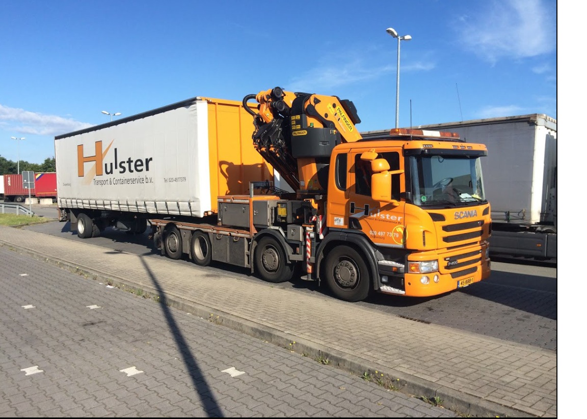 Vrachtwagen met laadkraan en oplegger voor transport en laden van goederen bij distributiecentrum