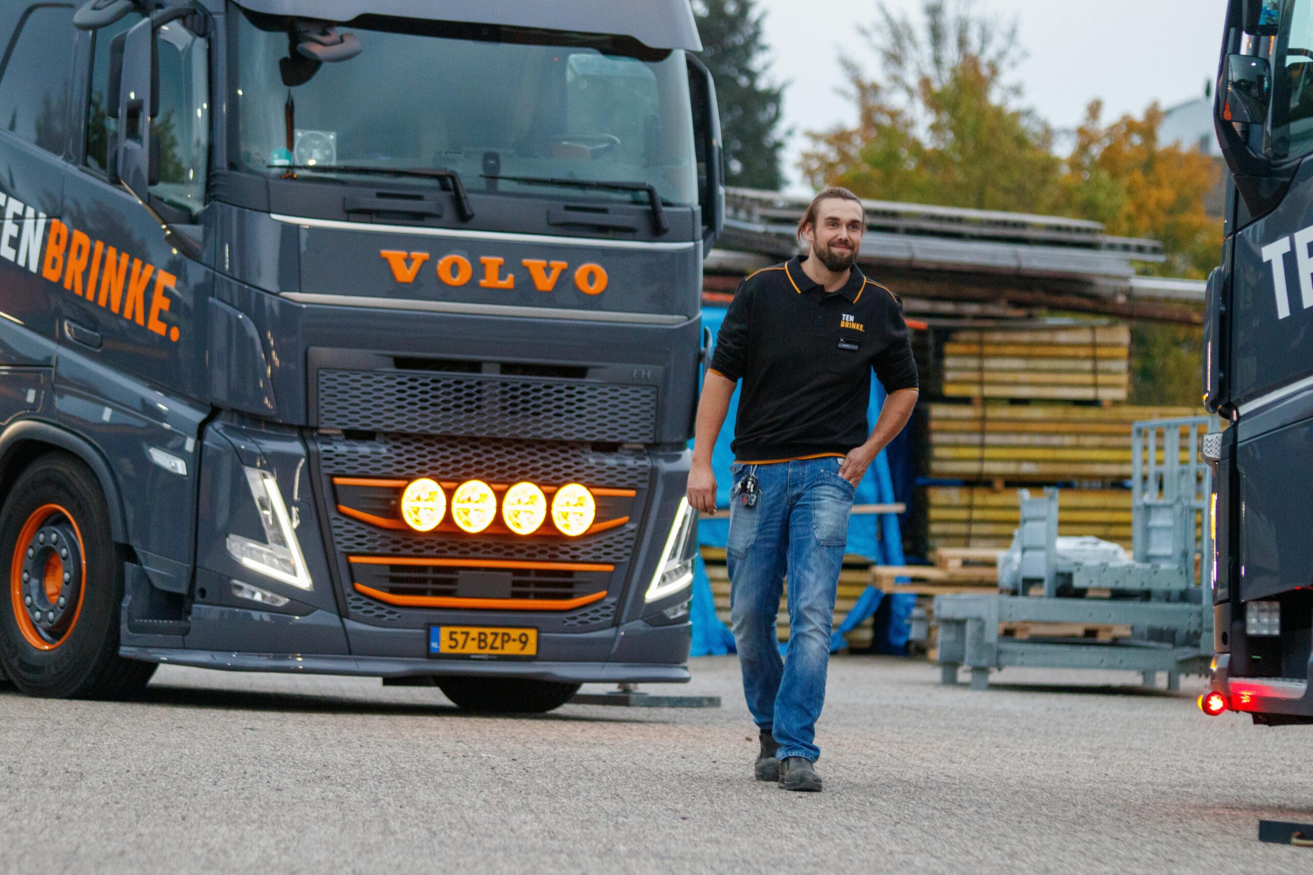 Vrachtwagenchauffeur loopt over transportterrein langs geparkeerde vrachtwagens bij logistiek bedrijf